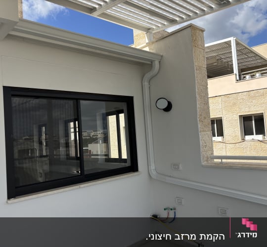 גג עם פרגולה מתכתית וחלון זכוכית גדול